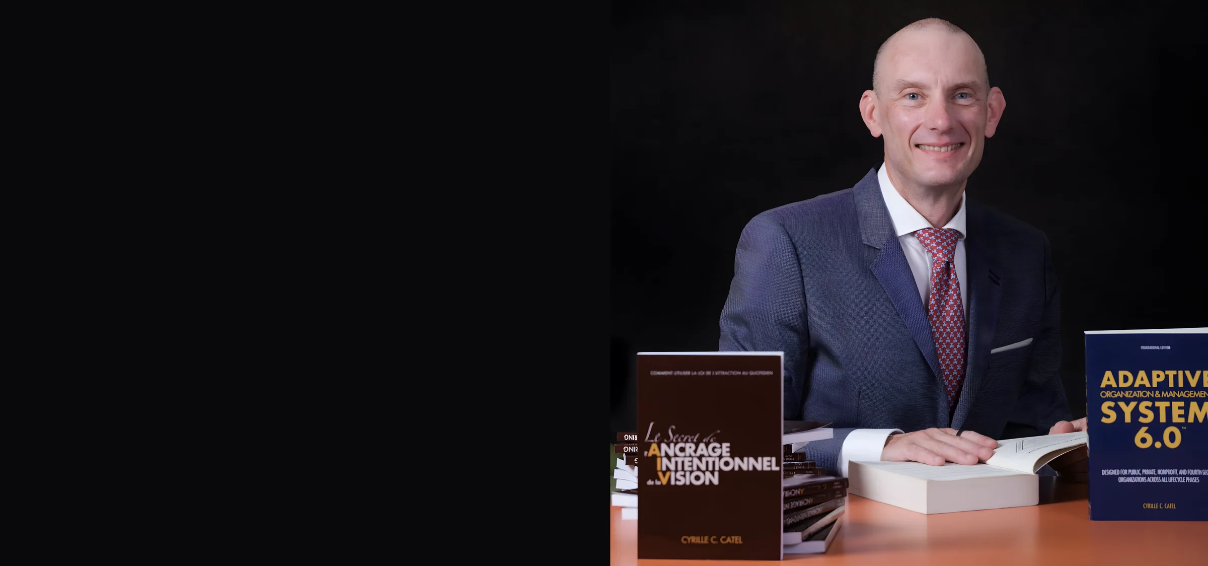 Cyrille C. Catel seated with his two published books, AOMS 6.0™ and Intentional Vision Anchoring, on a dark studio background.